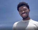Lil Nas X, uśmiechnięty na tle błękitnego nieba. Czy Lil Nas X jest gejem? To pytanie często pojawia się w dyskusjach o jego życiu.