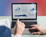 Ręce analizują wykresy na laptopie, przygotowując materiały do seo bloga.