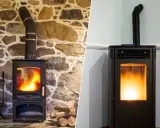Comparaison de deux poêles : un poêle à bois traditionnel sur fond de pierre et un poêle à granulés moderne. Idéal pour installer un poêle à pellet.