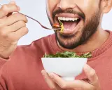 Mann isst Salat, achtet auf die richtige Anzahl, wie oft kauen, für eine gute Verdauung.
