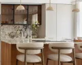 Cocina moderna con isla central, taburetes y electrodomésticos integrados. Un diseño atemporal que combina funcionalidad y elegancia.