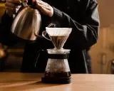 Person gießt heißes Wasser über Kaffeepulver in einem Filter. Die richtige filterkaffee temperatur ist entscheidend für den Geschmack.