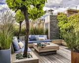 Un coin salon confortable pour aménager une terrasse avec des coussins bleus, une table basse en bois et une végétation luxuriante.