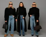 Trzy kobiety w czarnych, obszernych płaszczach i jeansach. Modny styl oversize.