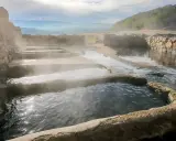 Tierras de vapor y agua en las termas naturales Galicia. Un paisaje sereno con piscinas escalonadas y muros de piedra.