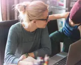 Une mère travaille sur son ordinateur portable, son enfant curieux s'approche. Un moment de vie quotidienne illustrant l'équilibre digital.