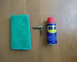 Ściereczka, mosiężny element i puszka WD-40 – wszystko gotowe do czyszczenia mosiądzu.