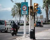 Señal de zona de bajas emisiones en Vigo. Coches y motos circulan bajo palmeras.
