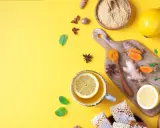 Zutaten für antivirale Lebensmittel: Ingwer, Kurkuma, Zitrone, Honig und Minze auf gelbem Hintergrund.