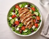 En fräsch sallad med grillat kyckling innanlår, tomater, gurka, oliver och fetaost.