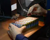 Un technicien assemble des cellules pour comment reparer une batterie de velo electrique. Il utilise un outil de soudure par points.