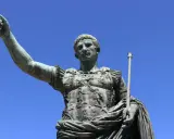 Bronzestatue eines römischen Kaisers, der mit erhobener Hand und Zepter auf den Betrachter blickt. Sie symbolisiert, wie wurde Rom regiert.