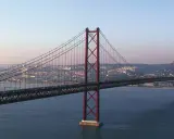 Der rote Hängebrücken-Gigant, oft als "Golden Gate Lissabon" bezeichnet, überspannt das ruhige Wasser mit der Stadt im Hintergrund.