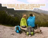 Para wybrać co zabrać w góry latem, lista sprzętu jest kluczowa. Para turystów z plecakami podziwia widok.