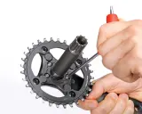 Hände demontieren eine SRAM Kurbel mit einem Inbusschlüssel.
