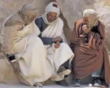 Drei Männer in traditioneller Kleidung sitzen und unterhalten sich. Sie diskutieren vielleicht, was haben Araber erfunden, während sie die Sonne genießen.