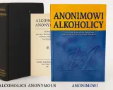 Trzy książki: czarna z napisem "Alcoholics Anonymous", kremowa z tekstem "Alcoholics Anonymous" i niebiesko-żółta z tytułem "Anonimowi Alkoholicy".