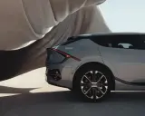 El elegante diseño de un vehículo eléctrico gris, con su distintiva luz trasera, se revela bajo una tela flotante.