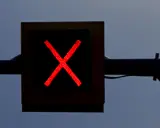 Czerwony znak ostrzegawczy w kształcie litery X na czarnym tle.