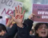 Mano alzata con "STOP" scritto in rosso, simbolo di protesta. Si evoca la necessità di una **codice rosso procedura** per proteggere le vittime.
