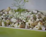 Pyszna sałatka z makaronem, szynką, ogórkiem i serem, udekorowana świeżym koperkiem.