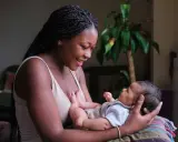Eine junge Frau hält ihr Baby liebevoll im Arm. Die Frage "wie lange kann man stillen" beschäftigt viele Mütter.