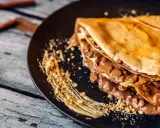 Crepe doblada con relleno cremoso de chocolate y trocitos de frutos secos. Una deliciosa receta crepes para disfrutar.