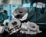 Mechanik w rękawiczkach prezentuje części turbosprężarki. Dowiedz się, ile kosztuje regeneracja turbiny w Bosch Service.