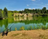 Wędkarskie popołudnie nad malowniczym jeziorem świętokrzyskim. Spokojna tafla wody odbija skaliste zbocza porośnięte zielenią.