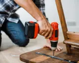 Un homme assemble un meuble en bois avec une perceuse. Un projet de bricolage maison réussi.