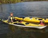 Två gula kajaker på vattnet, en med en ung man som deltar i en kajak kurs. En annan person syns i den bakre kajaken.
