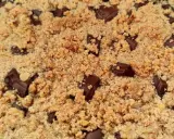 Gros plan sur un délicieux crumble pomme amande parsemé de morceaux de chocolat noir fondants.