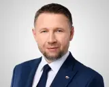 Mężczyzna w granatowym garniturze, z krótkimi włosami i zarostem, to minister spraw wewnętrznych.
