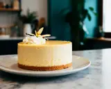 Gâteau rond et crémeux, une délicieuse mousse vanille sur une base biscuitée, couronné de chantilly et d'une fleur de vanille.