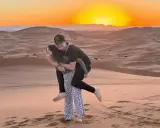 Jóvenes disfrutando de un atardecer en las dunas de Marruecos con niños.
