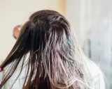 Nasse Haare, die nur mit Wasser gewaschen wurden, werden von einer Hand durchkämmt.