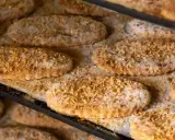 Varias cocas de llardons recién horneadas, cubiertas de azúcar y trocitos de frutos secos, listas para disfrutar.
