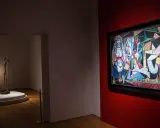 A museum gallery showcases Picasso's "Les Femmes d'Alger" alongside a slender bronze sculpture.