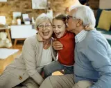 Nonna e nonno abbracciano felici la nipote. Un momento di gioia che sottolinea il diritto dei nonni a vedere i nipoti, un legame prezioso.