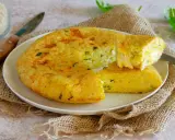 Una gustosa frittata di riso dorata, con erbe aromatiche, servita su un piatto bianco con una fetta tagliata.