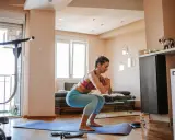 Frau macht Kniebeugen auf einer Matte, ein Beispiel für effektives **Eigengewicht Training** zu Hause.