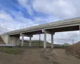 Un puente de hormigón cruza vías de tren. Los pilares de soporte, que son un estribo, sostienen la estructura. El cielo está nublado.