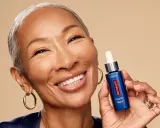 Mujer sonriente muestra un sérum Revitalift con retinol, ideal para rejuvenecer la piel y combatir arrugas.