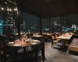En mysig restaurang i Stockholm med vacker utsikt över stadens ljus på natten. Eleganta bord med dukning och bekväma sittplatser.
