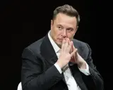 Elon Musk, znany wizjoner i przedsiębiorca, w czarnym garniturze, z dłońmi złożonymi przed twarzą.