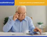 Starszy mężczyzna w okularach, z długopisem w dłoni, korzysta z tabletu. Dyskutuje o ochronie przedemerytalnej.