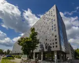 Nowoczesny budynek SWPS Wrocław z okrągłymi oknami, pod błękitnym niebem z chmurami.