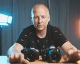 Mężczyzna z aparatami przed sobą, gotowy do rozpoczęcia kursu fotografii.