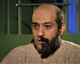 Uomo con barba da un lato, calvo dall'altro, dietro le sbarre. Potrebbe essere il protagonista de "il cacciatore di anoressiche libro".