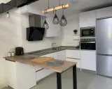 Cocina moderna con isla, electrodomésticos integrados y lámparas colgantes. Ideas para como diseñar una cocina funcional y elegante.